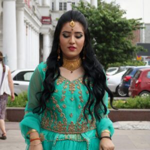 Elegant woman in a traditional green dress, standing on a city street.