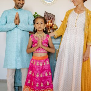 A happy Indian family in traditional attire celebrating a cultural event indoors.