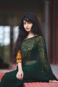 Beautiful woman posing in a traditional green sari with intricate patterns, showcasing style and culture.