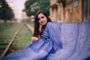 Portrait of a woman in a blue saree with intricate jewelry, captured outdoors.
